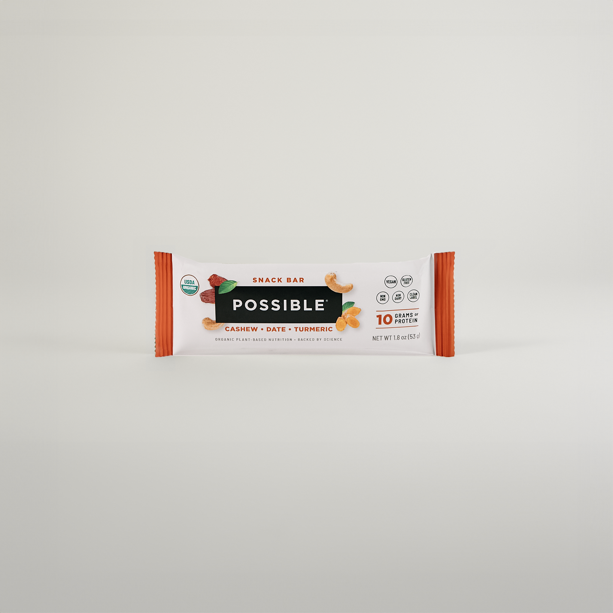 Minimalist display of a cashew turmeric date snack bar in its packaging against a clean white background.