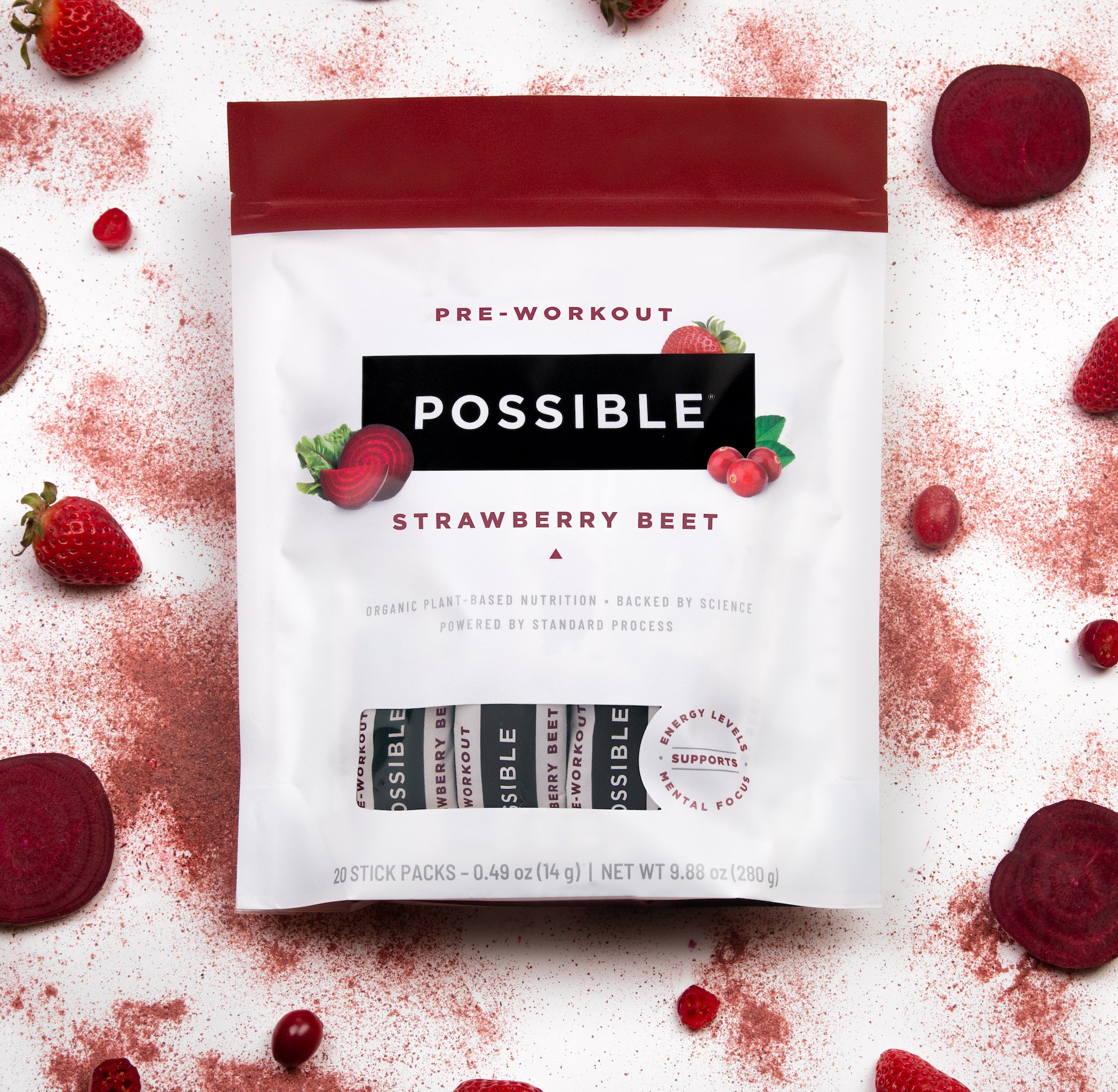 Flat-lay composition of POSSIBLE Pre-Workout Strawberry Beet pouch with scattered beets and powdered supplement for a modern product display